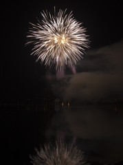 Colorful fireworks on black sky background with water reflection