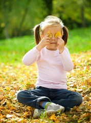 Little girl is playing in autumn park