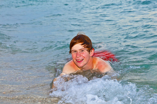 boy lying at the beach enjoys the surf of the ocean
