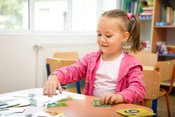 Cute little girl is playing with educational cards