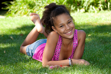 Naklejka na ściany i meble Young black teenage girl lying on the grass
