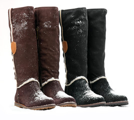 Two pairs of knee-high female boots covered with snow