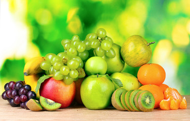 Ripe juicy fruits on wooden table on green background