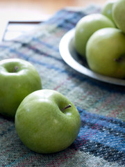 Granny smith apples sitting on a wool plaid blanket