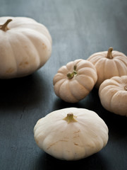 white pumpkins and squash sitting on a rustic black wooden board