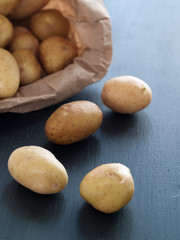 Fototapeta na wymiar White baby potatoes spilling out of brown bag