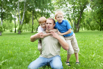 Naklejka na ściany i meble Portrait of father with two sons outdoor