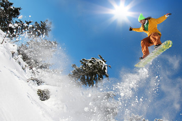 Snowboarder jumping against blue sky