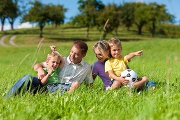 Family with children and football on a meadow