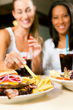 Zwei Frauen essen Hamburger und trinken Cola