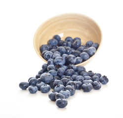 Blueberries spilling out of a pottery bowl.