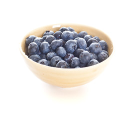 Blueberries spilling out of a pottery bowl.
