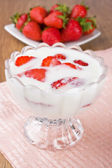 Fresh yogurt in glass bowl and ripe strawberry
