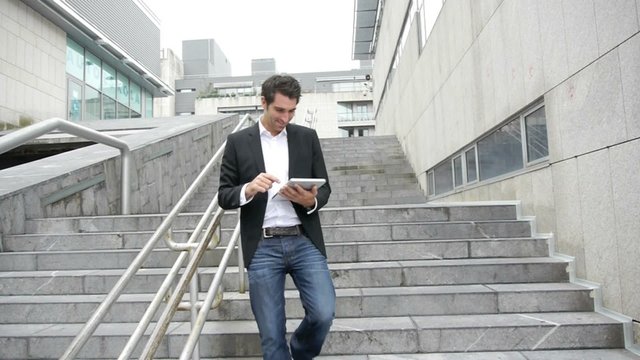 Man using electronic tablet while walking downstairs