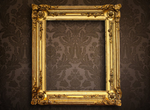 Empty golden painting frame on vintage wallpaper