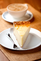 Cheesecake and a cup of cappuccino in background