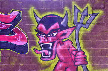 Devil graffiti on a brick wall