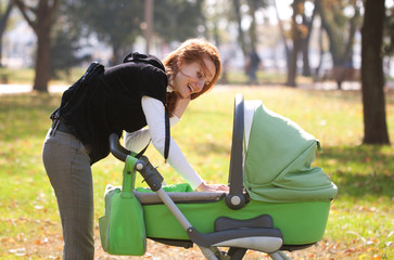 Young mother carrying baby in autumn park