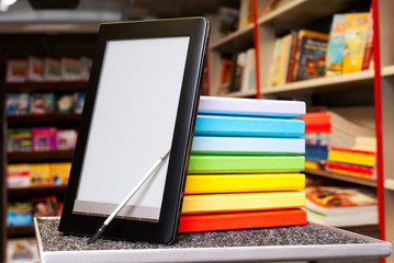 Stack of colorful books with electronic book reader