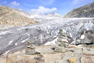 Stacked rocks with blue sky and Rhone glacier as background