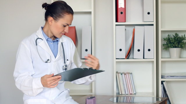 Happy female doctor with clipboard in the office
