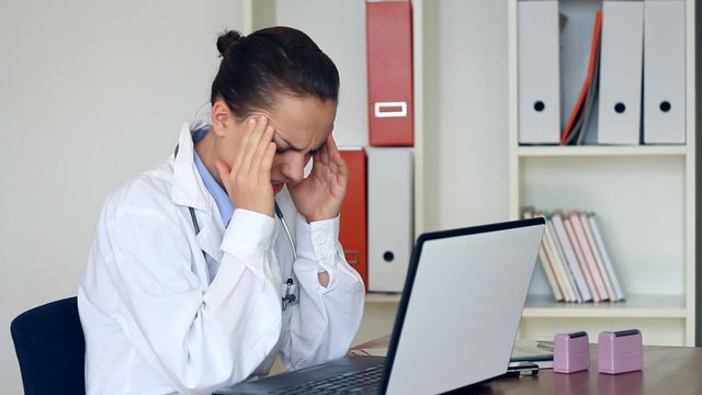 Young female doctor having headache in the office