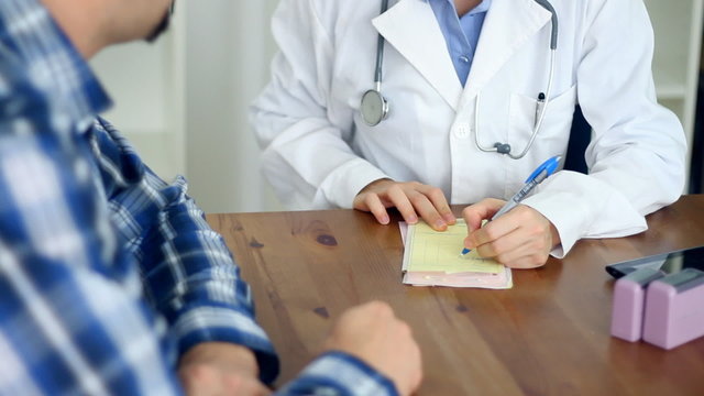 Female doctor writing rx prescription for male patient