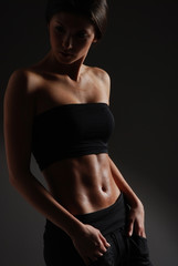 A young and sexy brunette woman in black sporty clothes