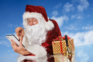 Santa Claus with tablet pc, gift and bell