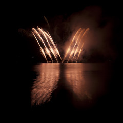 Colorful fireworks on black sky background with water reflection