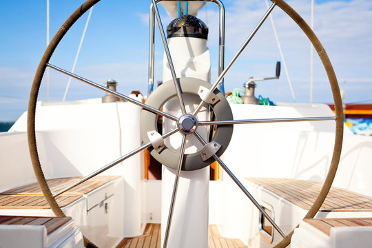 A steering wheel on a boat with empty seats.