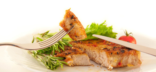 Meat, an onion and pepper on a grill, a fork with a knife