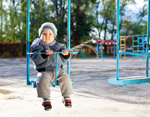 baby boy playing on swing in autumn park