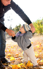 baby boy taking first steps with father help