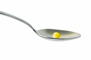 Pill in a spoon on a white background