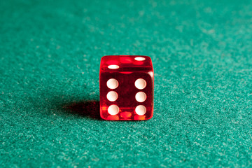 Detail of one red dice on green table