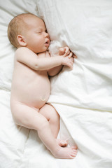Newborn child on white blanket.