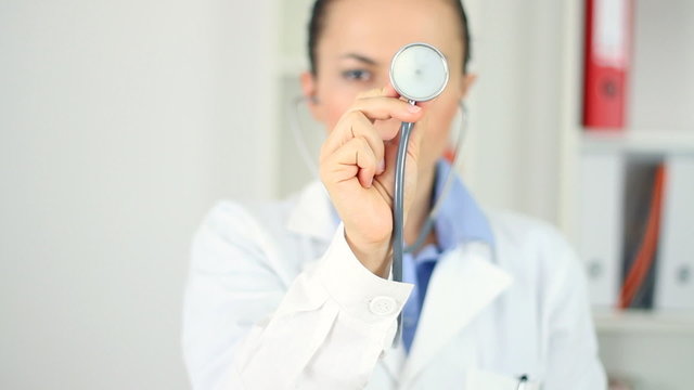 Female doctor holding stethoscope and pointed toward camera
