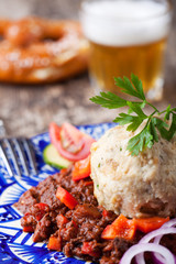 Gulasch mit Knödel auf blauem Teller