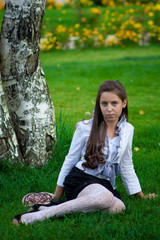teen sitting near the birch on the green grass