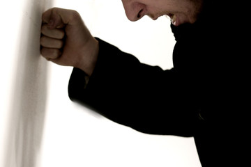 mann schlägt mit faust gegen wand