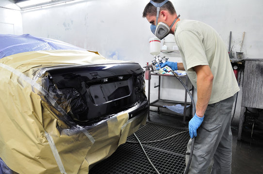 Worker painting a car.