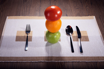 Obst und Gemüse auf Untersetzer mit Besteck angerichtet