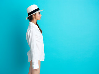 young woman blue background white hat, shirt
