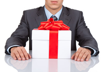 Businessman sitting at the desk with gift box isolated
