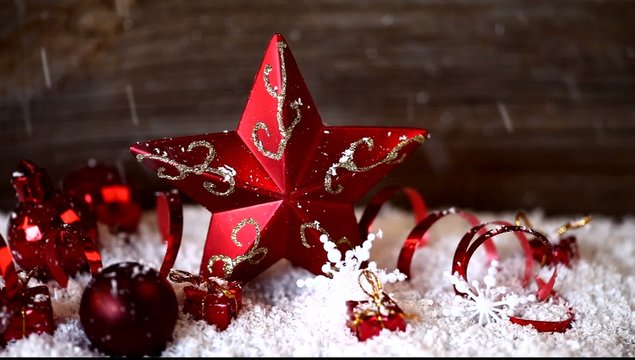 snow falling on red star and christmas ball ornaments