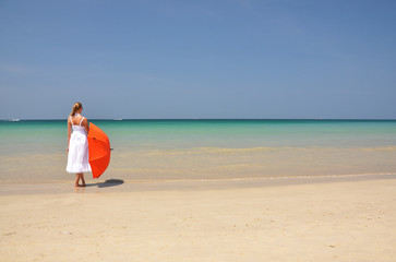 Fototapeta premium Girl with an orange umbrella on the sandy beach