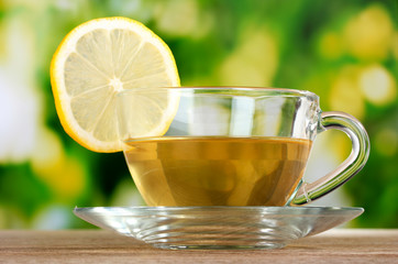 tea with lemon on green leaves background