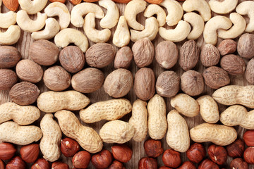 nutmeg, peanuts, hazelnuts and almonds on wooden background