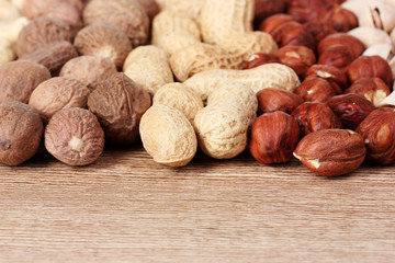 nutmeg, peanuts, hazelnuts and almonds on wooden background